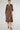 Woman wearing a brown button down satin dress with a belt on a white background