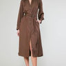 Woman wearing a brown button down satin dress with a belt on a white background
